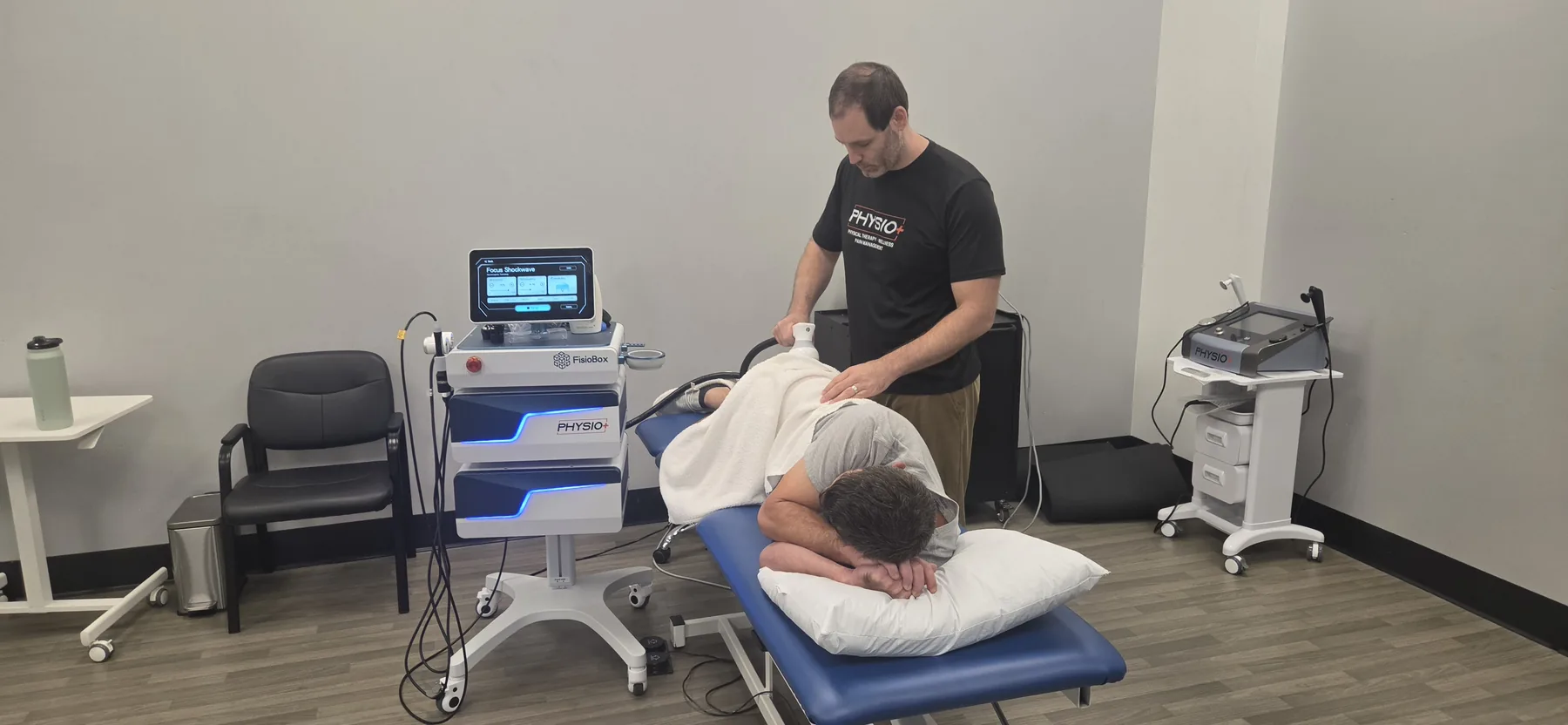 A Physio+ doctor of physical therapy treating a patient with the focused shockwave unit at the Lindale clinic